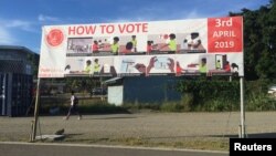 FILE - A boy walks past a sign with voting instructions on his way to school in Honiara, Solomon Islands, March 11, 2019. 