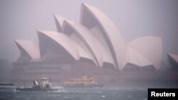 FILE - Ferries and boats pass in front of the Sydney Opera House as strong winds and heavy rain hit the city of Sydney, Australia, Nov. 28, 2018. 