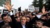 Ekrem Dumanli, editor-in-chief of Zaman newspaper, salutes cheering supporters as he is detained outside his office in Istanbul, Turkey, Dec. 14, 2014. 