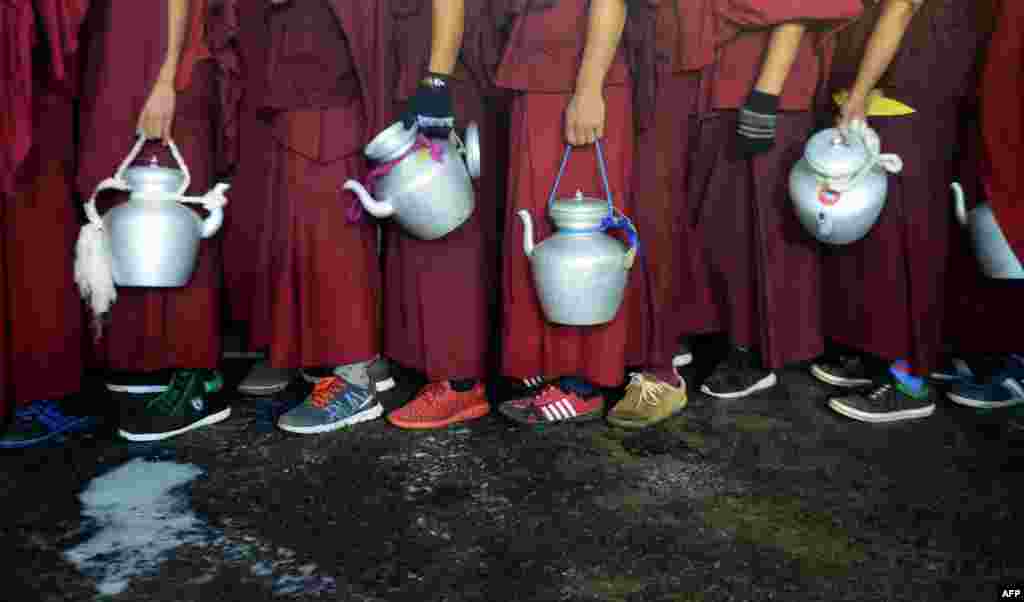 Tibetan Buddhist monks wait to collect boiling milk to distribute to devotees who are participating in a special religious prayer attended by Tibetan spiritual leader The Dalai Lama during the Kalachakra event at Bodhgaya, India.