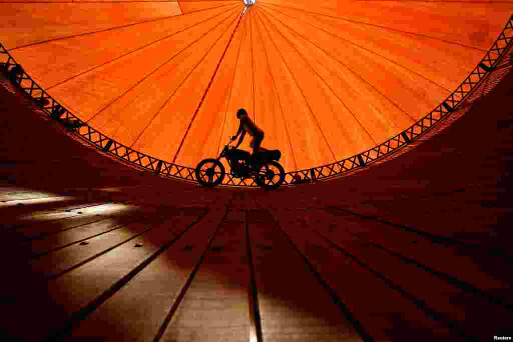 A stuntman rides a motorcycle inside the "Well of Death" attraction during a fair in Bhaktapur, Nepal.
