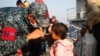 A Bangladesh navy personnel helps a child to wear a mask due to ongoing coronavirus disease (COVID-19) before getting on board a ship to move to Bhasan Char island in Chattogram, Bangladesh, Dec. 29, 2020.