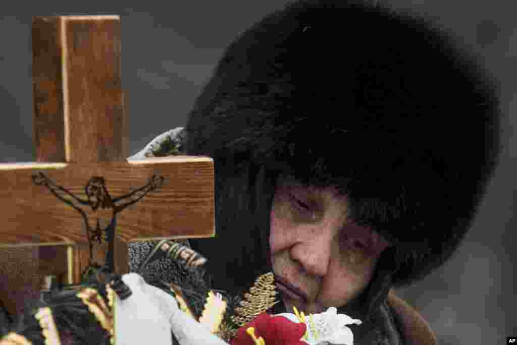 The mother of Elena Volkova, a victim of shelling, cries at her daughter's grave during her funeral in Avdiivka, eastern Ukraine.