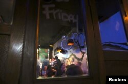 FILE - Patrons are reflected in a mirror as they drink at the York Lane Bar located in Sydney, Australia.