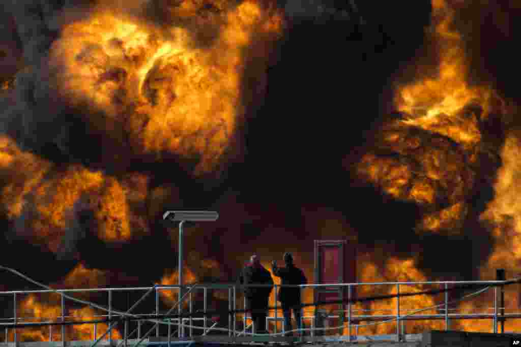 Workers watch fire fighters fight flames in a fuel tank in Oil Refineries Ltd in Haifa bay, Israel.