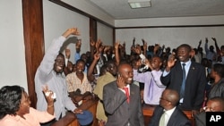 Uganda's top opposition leader Kizza Besigye's, second left, waves to supporters inside the court in Kampala, Uganda after he was freed on bail, March 28, 2012.