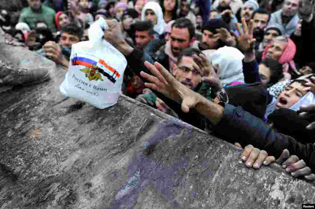 Syrians, who have been evacuated from eastern Aleppo, reach out for Russian food aid in government-controlled Jibreen area in Aleppo.
