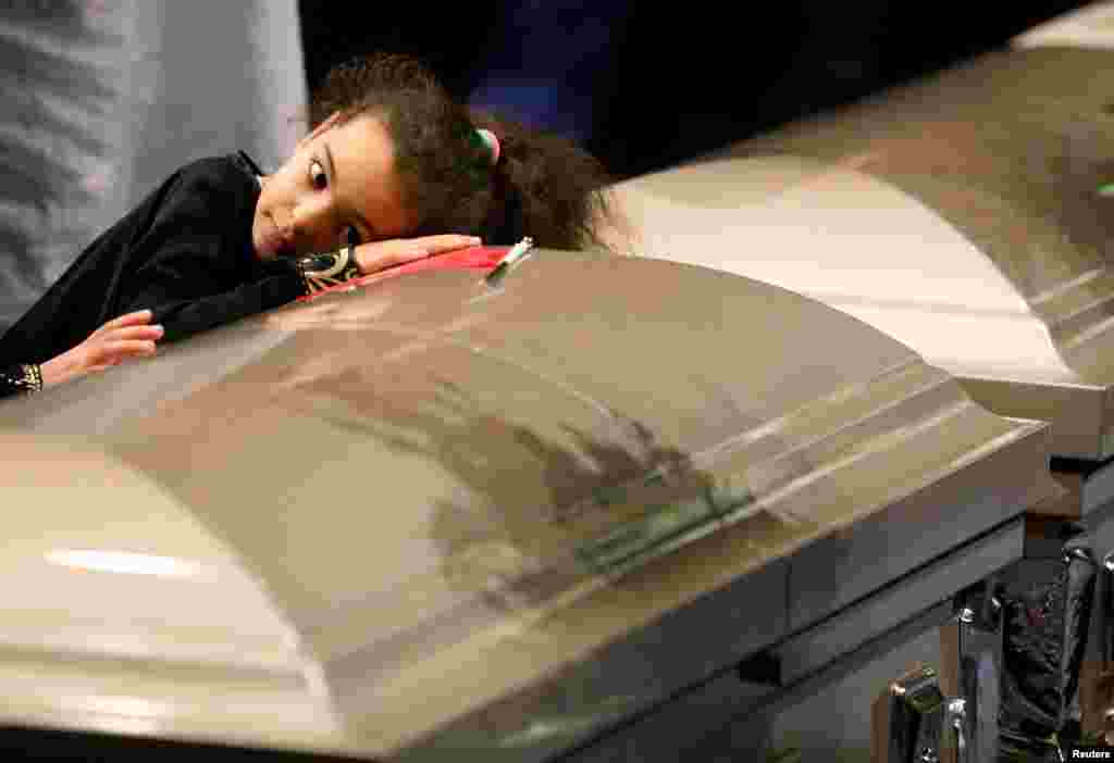 A young mourner lays her head on one of the caskets during funeral services for three of the victims of this week&#39;s deadly shooting at the Quebec Islamic Cultural Center, at the Congress Center in Quebec City, Quebec.