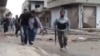 Image made from amateur video purports to show a Syrian rebel helping an injured man in Rastan, Homs, Syria.