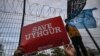 Seorang pendukum kelompok minoritas Muslim Uighur memegang spanduk bertuliskan "Selamatkan Uighur" sedangkan seorang anak melambaikan bendera Turkestan Timur dan bendera hitam dalam demo di depan Konsulat Jenderal China di Istanbul, Turki, 13 Desember 201