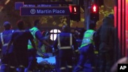 FILE - Armed tactical response officers and emergency workers attend the scene after a cafe siege in the central business district of Sydney , Australia.