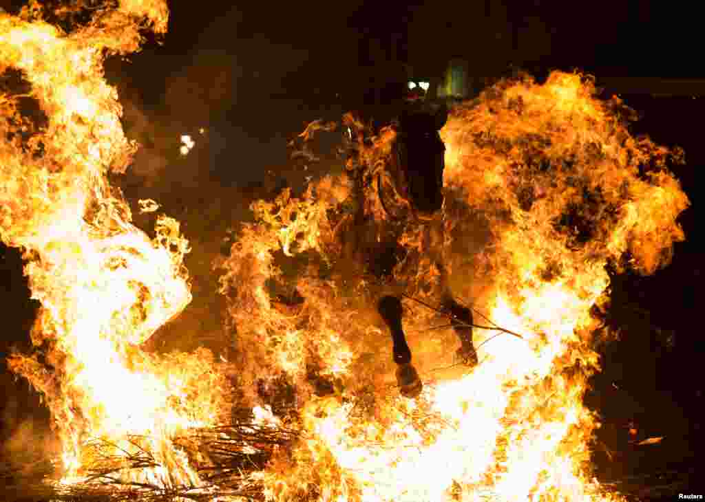 A man rides a horse through the flames during the "Luminarias" annual religious celebration on the eve of Saint Anthony's day, Spain's patron saint of animals, in the village of San Bartolome de Pinares, northwest of Madrid, Jan. 16, 2017.