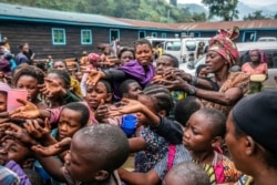 FILE - People who fled Goma, Congo, gather at a food distribution point in Sake, some 25 kms (16 miles) west of Goma, where they found shelter following an official evacuation order, May 28, 2021.