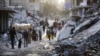 Warga Palestina yang mengungsi akibat serangan udara dan darat Israel di Jalur Gaza, berjalan melewati aliran limbah gelap yang mengalir ke jalan-jalan kota selatan Khan Younis, Jalur Gaza, pada 4 Juli 2024. (Foto: AP)