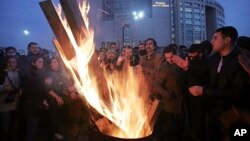 Cheering fans of the Besiktas soccer team gather around a fire outside a courthouse as a trial of dozens of football fans proceeds inside in Istanbul, Dec. 16, 2014.