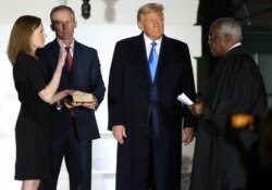 Judge Amy Coney Barrett is sworn in to serve as an associate justice of the U.S. Supreme Court by Supreme Court Justice Clarence Thomas as her husband Jesse Barrett and President Donald Trump watch on the South Lawn of the White House in Washington.