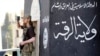 FILE - A militant Islamist fighter uses a mobile to film his fellow fighters taking part in a military parade along the streets of Syria's northern Raqqa province.