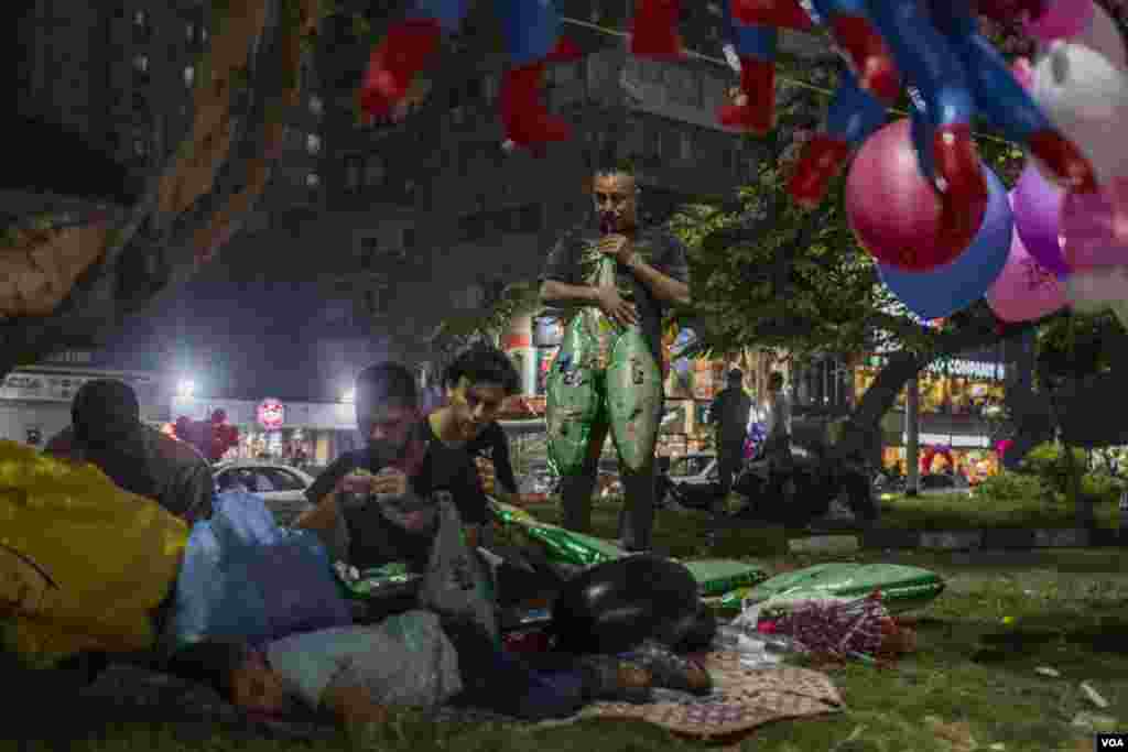 Ballon vendors blow balloons as they are getting ready for the customers to come and attend the prayers of Eid Al-Fitr nearby in Cairo, Egypt, June 25, 2017. (H. Elrasam/VOA)