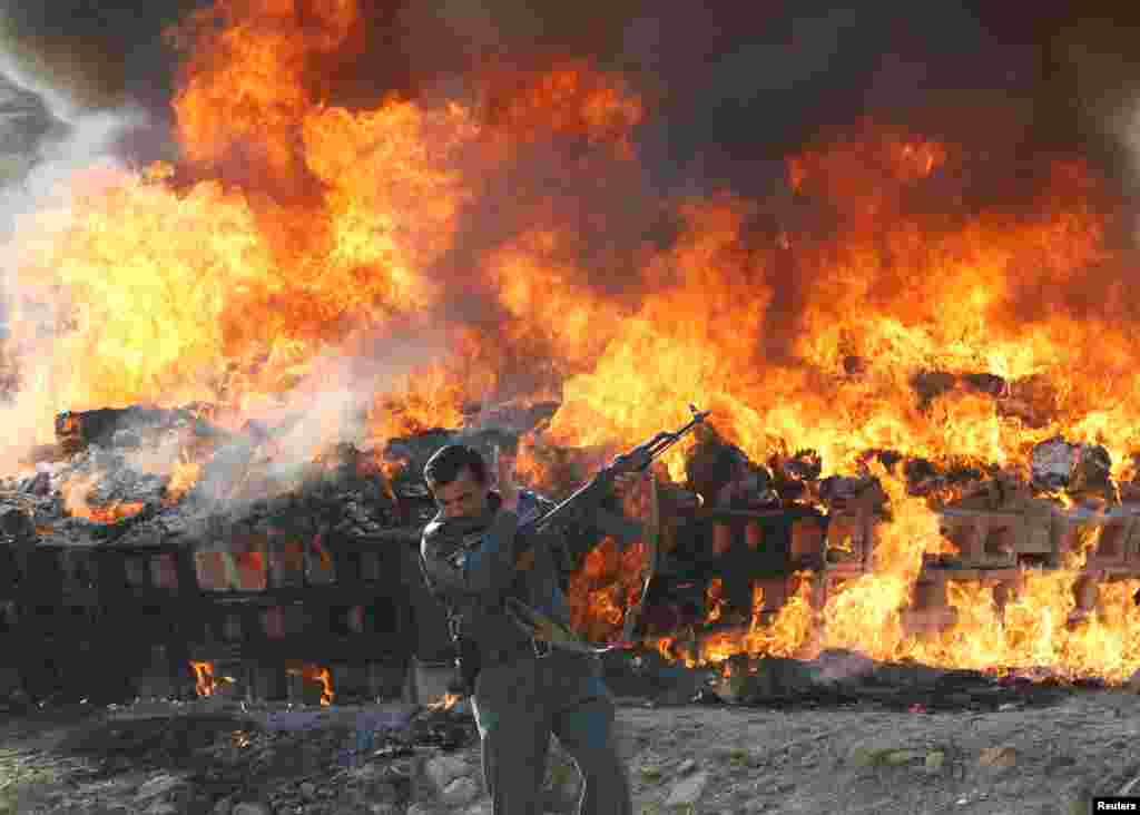 An Afghan officer reacts in front of a burning pile of seized narcotics and alcoholic drinks, in the outskirts of Kabul.