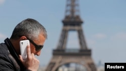 FILE - A man makes a phone call using his mobile phone at the Trocadero Square near the Eiffel Tower in Paris, May 16, 2014. 