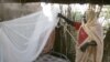 A Sudanese women sets up a bed net (file photo)