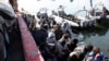 Migrants sit in a port, after being rescued at sea by Libyan coast guard, in Tripoli, Libya, April 11, 2016.