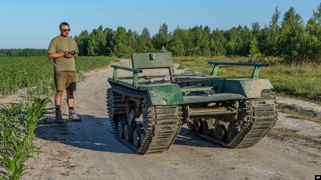 "UkrPrototyp" dizayn va ishlab chiqarish byurosining bosh direktori Andriy Denysenko Ukraina shimolidagi makkajo'xori dalasida 800 kilogrammlik quruqlikdagi avtonom harakatlanuvchi transport prototipi yonida, 2024 yil, 28-iyun.