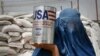 FILE - An Afghan woman carries a container of vegetable oil donated by United States Agency for International Development (USAID), in Kabul, Afghanistan, July 26, 2011.