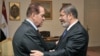In this photo released by Middle East News Agency, caretaker Prime Minister Kamal el-Ganzouri, left, shakes hands with newly elected President Mohamed Morsi in Cairo, June 25, 2012.