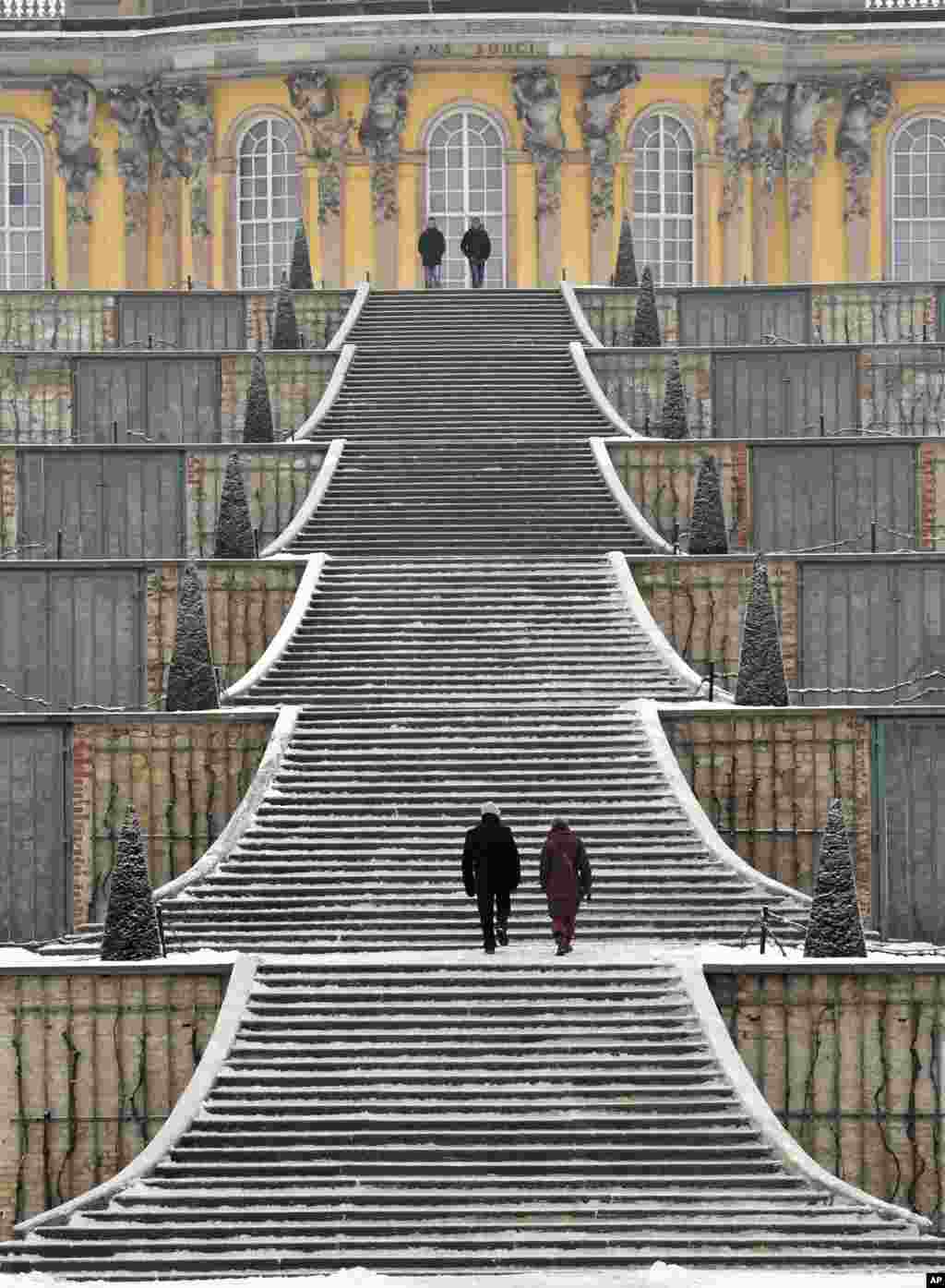 Tourists take the snow-covered steps at Sanssouci Palace in Potsdam, Germany.