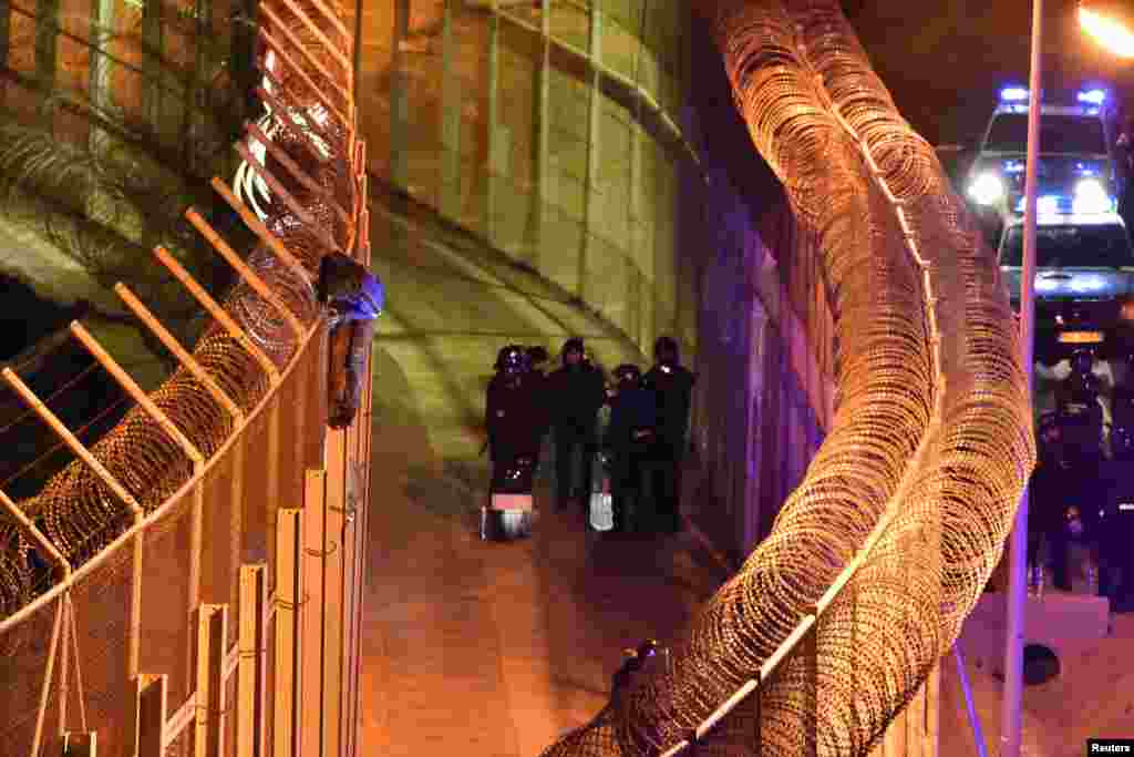 An African migrant stands on top of a border fence as Spanish police stand guard below during a failed attempt to cross into Spanish territories, between Morocco and Spain's north African enclave of Ceuta, Jan. 1, 2017.