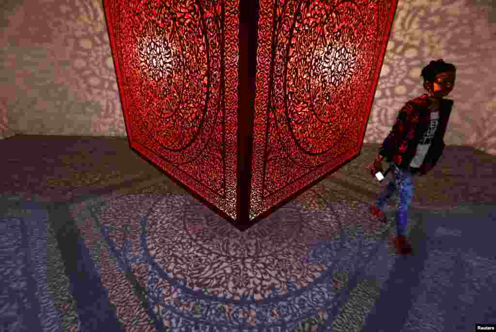 A visitor walks next to an exhibit titled "All The Flowers Are For Me" by Pakistani-American artist Anila Quayyum Agha at the India Art Fair in New Delhi.