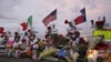 FILE - Flags fly over crosses at a makeshift memorial near the scene of a mass shooting, Aug. 4, 2019, at a shopping complex in El Paso, Texas, Aug. 6, 2019.