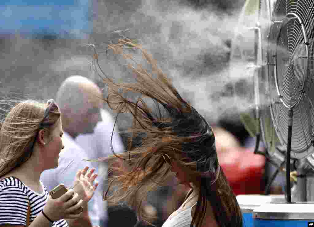 A spectator cools herself at a water spraying fan at the Australian Open tennis championships in Melbourne, Australia.