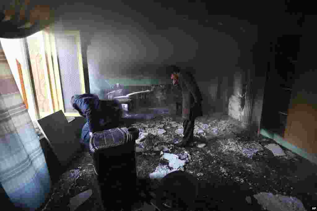 Afghan men inspect the remains of their belongings at the house of parliament member Mir Wali in the aftermath of gunmen's attack in western Kabul.