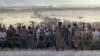 FILE - Turkish soldiers stand guard as Syrians wait behind border fences near the southeastern town of Suruc, Sanliurfa province, Sept. 2014.