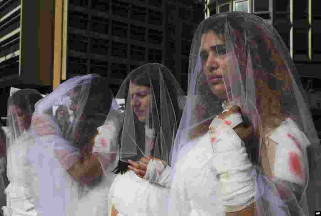 A dozen Lebanese women, dressed as brides in white wedding dresses - stained with fake blood and bandages all over thier bodies - protest against a law that allows a rapist to get away with his crime if he marries the survivor, in front of the government building in downtown Beirut.