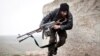 FILE - In this December 17, 2012 file photo, a Free Syrian Army fighter takes cover during fighting with the Syrian Army in Azaz, Syria.