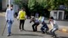 An Indian policeman, left and a civil defense person, second left, make people perform sit ups while holding their ear lobes, as a punishment for stepping out without a valid reason during a lockdown in Ahmedabad, India, Tuesday, March 24, 2020. 