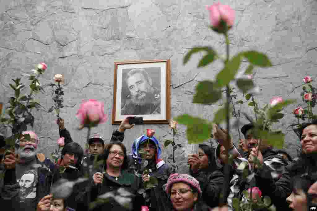 People hold flowers in front of a portrait of Cuban historic revolutionary leader Fidel Castro at the Cuban embassy in Bogota, Colombia, Nov. 26, 2016. Fidel Castro died late Friday in Havana, his brother, President Raul Castro, announced on national television. Castro's ashes will be buried in the historic southeastern city of Santiago on Dec. 4 after a four-day procession through the country.