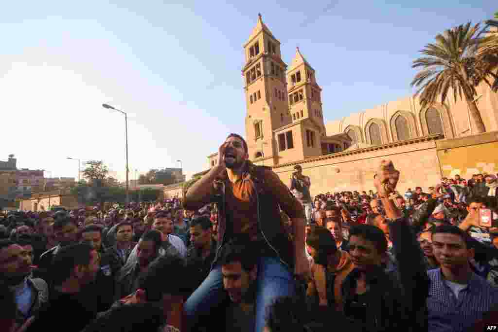 Egyptians shout slogans as they gather outside the the St. Peter and St. Paul Coptic Orthodox Church in Cairo's Abbasiya neighborhood after it was targeted by a bomb explosion. The blast killed at least 25 worshipers during Sunday Mass inside the church near the seat of the Coptic pope who heads Egypt's Christian minority, state media said.