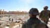 In this picture taken Friday, April 1, 2016, soldiers look over damage at the historical Bel Temple in the ancient city of Palmyra in the central city of Homs, Syria.