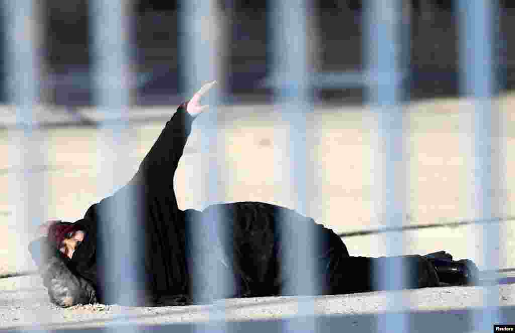 A Palestinian woman, who according to the Israeli police was shot and wounded after she attempted to stab Israeli officers, lies on the ground at Qalandiya checkpoint near the West Bank city of Ramallah.