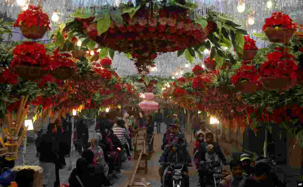 Motorcyclists drive through a street decorated with flowers on the eve of celebrations marking the birth of Islam's Prophet Muhammad, in Lahore, Pakistan.