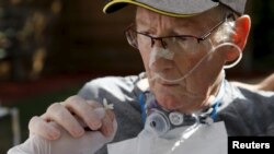FILE - A stroke patient holds a flower in the therapeutic garden of the Acute Neurological Rehabilitation Unit at Lausanne University Hospital in Lausanne, Switzerland, Aug. 25, 2015.