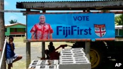 A FijiFirst poster with the image of Fiji Prime Minister Frank Bainimarama hangs at the entrance to a village in Nausori, Fiji, Nov. 7, 2018. Opinion polls indicate Bainimarama is poised to win a second term in Fiji's general election Wednesday after he f