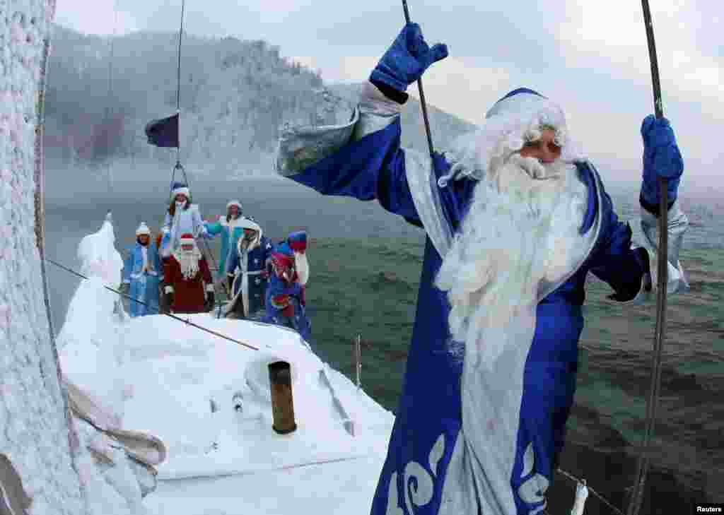 Members of the "Skipper" yacht club dressed as Ded Moroz, the Russian equivalent of Santa Claus, and his granddaughter Snegurochka (Snow Maiden) sail a yacht along the Yenisei River outside the Siberian city of Krasnoyarsk, Russia.